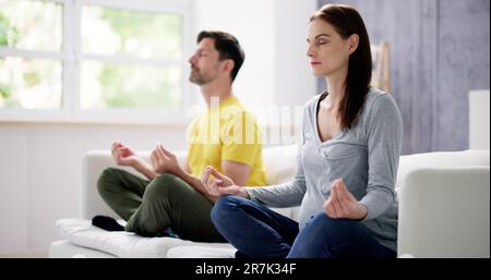 Méditation de yoga en famille sur le canapé. Fitness à la maison Banque D'Images