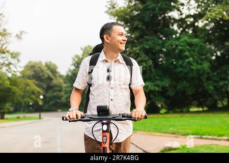 Un homme heureux qui fait du scooter électrique au parc Banque D'Images
