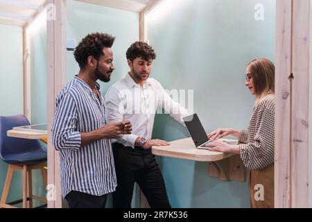 Collègues travaillant ensemble avec un ordinateur portable dans une armoire de bureau Banque D'Images