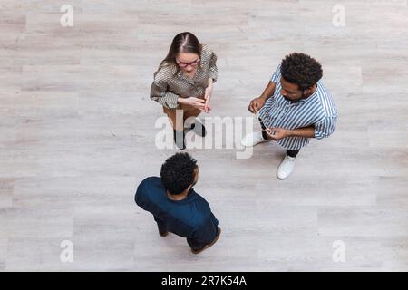 Vue en grand angle des collègues qui parlent sur un sol en bois Banque D'Images