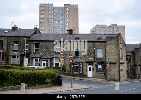 Les anciens ouvriers d'usine mirent des chalets dans les rues mitoyennes de Woodside, une partie de la région de Boothtown avec des blocs de tour élevés derrière, le 6th juin 2023, à Halifax, au Royaume-Uni. Boothtown est une banlieue située dans le quartier de Halifax, tout près du centre-ville. Son histoire a été dominée par les usines de l'industrie textile. Rawsons Mill, sur Old Lane, est maintenant désavoué et désigné comme un bâtiment classé d'importance patrimoniale. Halifax est une ville du quartier de Calborough dans le West Yorkshire et a été une ville de moulin prospère pendant la révolution industrielle. De nos jours, alors que la ville montre des signes positifs o Banque D'Images