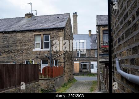 Les anciens ouvriers d'usine mirent des chalets dans les rues mitoyennes de Woodside, une partie de la région de Boothtown avec la cheminée de Rawsons Mill le 6th juin 2023 à Halifax, au Royaume-Uni. Boothtown est une banlieue située dans le quartier de Halifax, tout près du centre-ville. Son histoire a été dominée par les usines de l'industrie textile. Rawsons Mill, sur Old Lane, est maintenant désavoué et désigné comme un bâtiment classé d'importance patrimoniale. Halifax est une ville du quartier de Calborough dans le West Yorkshire et a été une ville de moulin prospère pendant la révolution industrielle. De nos jours, alors que la ville montre des signes positifs de Banque D'Images