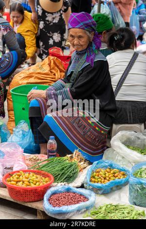 Bac Ha, Vietnam-avril 2023; vue verticale une femme de Flower Hmong et Giay qui vend des légumes sur le marché de bac Ha dimanche Banque D'Images