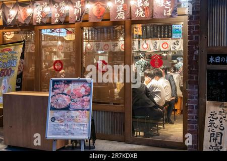 Tokyo, Japon-avril 2023 ; vue en soirée de la façade d'un petit restaurant dans le quartier Yurakucho sous des arches en briques (Gado-shita) de voies ferrées surélevées Banque D'Images