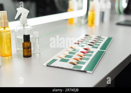 l'industrie de la beauté, la palette de couleurs des cheveux et différents outils de salon de coiffure sur la surface blanche, l'huile pour cheveux, les pulvérisateurs, le travail de salon, l'extension de cheveux, colorant capillaire Banque D'Images