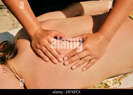Une femme masseuse montre un cœur avec ses doigts sur le dos d'une fille Banque D'Images