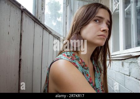 Beauté naturelle d'une jeune femme habillée dans une tenue vintage dans un intérieur grundy. Triste mélancholique femme caucasienne portant des vêtements boho chic dans un rusti Banque D'Images