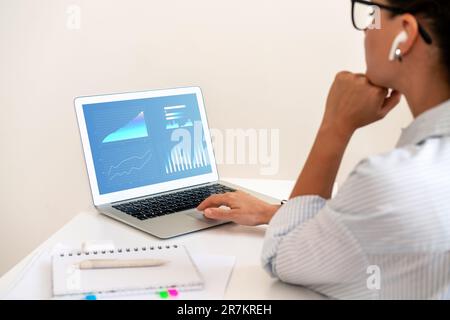 Jeune femme d'affaires travaillant sur son ordinateur portable, analysant les performances de l'entreprise à l'aide de graphiques de KPI commerciaux. Banque D'Images