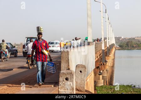 Homme transportant divers objets à la fin de la traversée du fleuve Niger par le Pont des Martyrs à Bamako, Mali. Banque D'Images