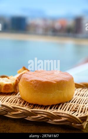 Fromage de vache fumé espagnol de Pria, Asturies, servi en plein air avec vue sur la plage de San Lorenzo et la promenade de Gijon Banque D'Images