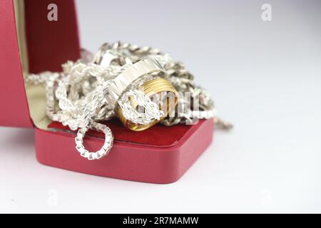 Bijoux en argent et en or dans une boîte sur fond blanc. De belles chaînes argentées et des anneaux dorés dans une pile de smal Banque D'Images