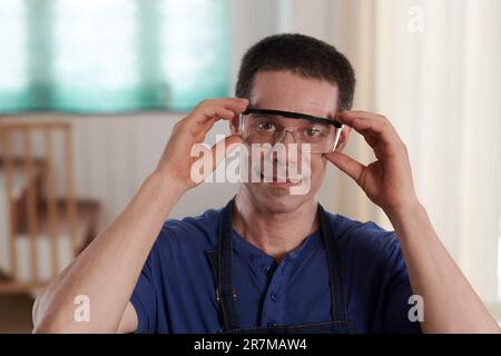 Portrait d'un jeune travailleur regardant l'appareil photo tout en portant des lunettes de protection pour travailler Banque D'Images
