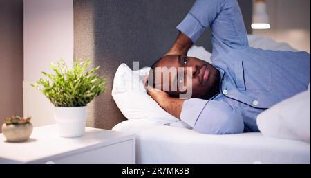Jeune homme africain souffrant de fièvre Lying On Bed Banque D'Images
