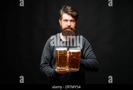Homme barbu souriant avec des tasses de bière. Alcool. Publicité au bar, au pub ou au restaurant. Homme élégant et élégant avec une bière en verre à la fête. Préparation du café. Durée de la bière Banque D'Images