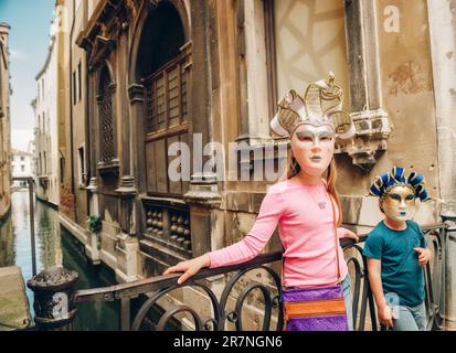 Deux enfants jouant avec des masques vénitiens célèbres. Petite fille et garçon en visite à Venise, Italie. Petits touristes portant des masques de carnaval souvenirs Banque D'Images