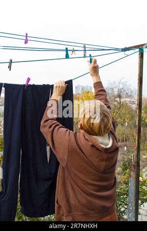 Buanderie une femme porte un chiffon humide propre sur le sèche-linge après avoir lavé à la maison. Travaux ménagers et entretien ménager Banque D'Images