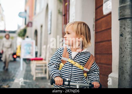 Portrait extérieur d'une petite fille adorable, à vélo, portant un sac à dos Banque D'Images