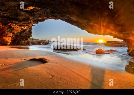 Soleil levant au-dessus de l'horizon de l'océan Pacifique depuis l'intérieur de la grotte de la mer dans la plage des Caves en Australie. Banque D'Images