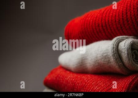 Motif de chandails tricotés colorés en gros plan. Produit en laine de mérinos fait main. Une pile de vêtements pliés avec des fleurs Banque D'Images