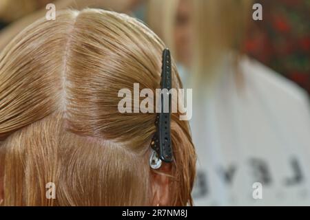 Femme aux cheveux blonds de longueur moyenne. Avec une courte coupe de cheveux au coiffeur au styliste à l'aide de ciseaux. Procédures d'entretien. Le maître raccourcit sa ha Banque D'Images