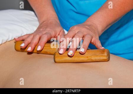 Concept bien-être. Un masseur professionnel donne à un homme un massage thaïlandais avec des bâtons de bambou au spa. Relaxation et récupération après le travail Banque D'Images