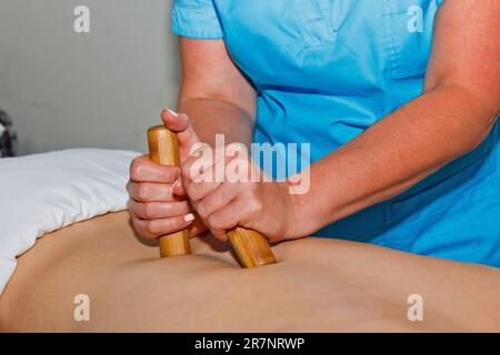 Concept bien-être. Un masseur professionnel donne à un homme un massage thaïlandais avec des bâtons de bambou au spa. Relaxation et récupération après le travail Banque D'Images