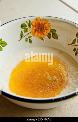 huile versée dans le lait dans un bol en métal. étape de préparation de la pâte. recette pâte feuilletée. gros plan sur les ingrédients de la cuisson. Banque D'Images