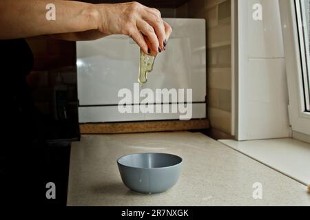 les mains des femmes cassent un œuf de poulet, en versant un bol sur le fond d'un intérieur de cuisine. cuisson, cuisson. Banque D'Images