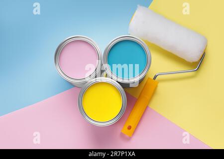 Boîtes avec différentes peintures et rouleau sur fond de couleur, à plat Banque D'Images