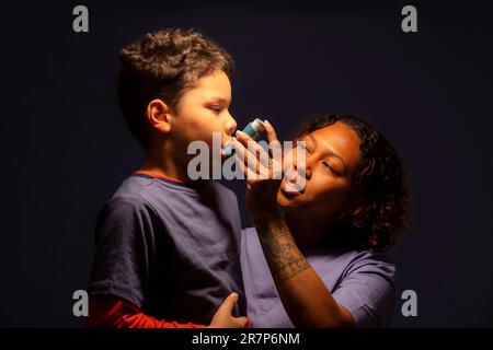 Professionnel de la santé aidant un garçon de 7 ans à utiliser un inhalateur. Banque D'Images