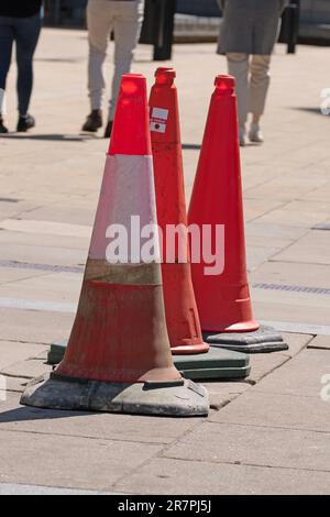 Trois cônes de signalisation orange sur une chaussée en ligne Banque D'Images