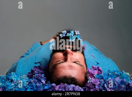 Homme qui ponte en fleurs. Corps mort. Homme barbu avec couché avec les yeux fermés Banque D'Images