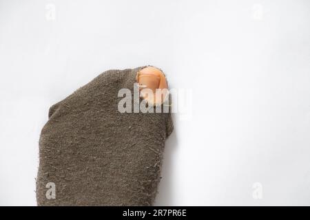 la pointe de la femme est sortie d'une chaussette déchirée sur un fond blanc gros plan, pieds féminins Banque D'Images