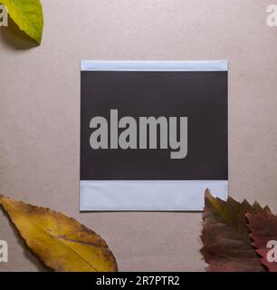 Cadre photo vierge avec des feuilles d'automne sur fond brun comme modèle pour la conception graphique. Carte photo avec espace Banque D'Images