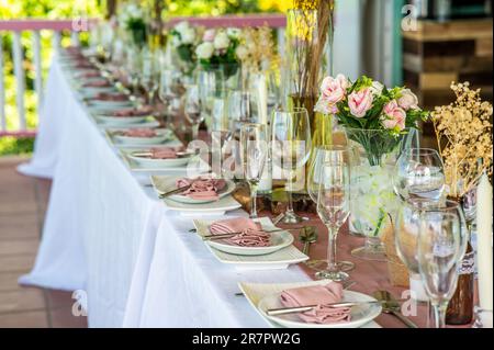 Une table en bois avec plusieurs assiettes blanches et des serviettes en papier blanc soigneusement disposées sur le dessus pour un mariage Banque D'Images