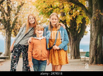 Portrait extérieur de 3 enfants amusants, deux filles et un garçon se posant ensemble dans le parc d'automne Banque D'Images