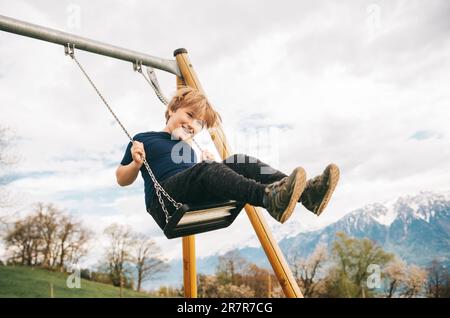 Enfant garçon s'amusant à balancer dans les alpes suisses, terrain de jeu avec belle vue Banque D'Images