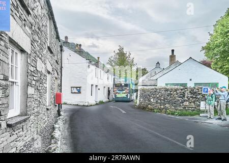 Un bus à impériale passe le long d'une route étroite à travers le hameau de Rosthwaite dans la vallée de Borrowdale, Lake District, Cumbria, Angleterre. Banque D'Images