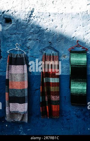 Des foulards sur un mur bleu vif : des foulards colorés ornent un arrière-plan bleu captivant, créant un affichage dynamique visuellement. Banque D'Images