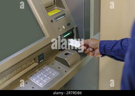 Main d'un homme insérant une carte vierge dans un guichet automatique. Banque D'Images