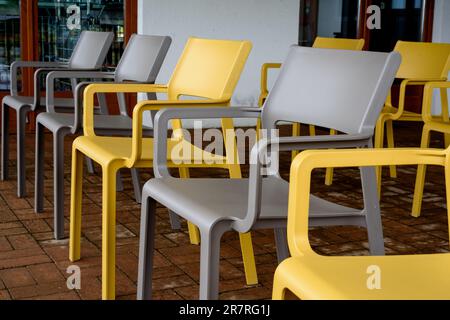 Chaises en plastique gris et jaune sur la terrasse Banque D'Images