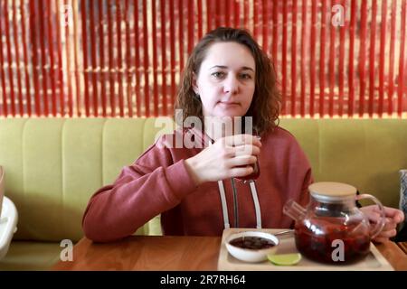 Femme qui boit du thé aux fruits avec de la confiture au restaurant Banque D'Images
