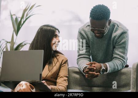 Une femme d'affaires brune a pris un coup d'œil à son petit ami noir après qu'il a joché avec elle pendant un certain temps. Il rit. Sourire léger sur son visage Banque D'Images