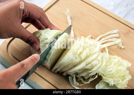 Les mains de femmes trancheuses de chou blanc sur planche en bois, cuisson étape par étape Banque D'Images