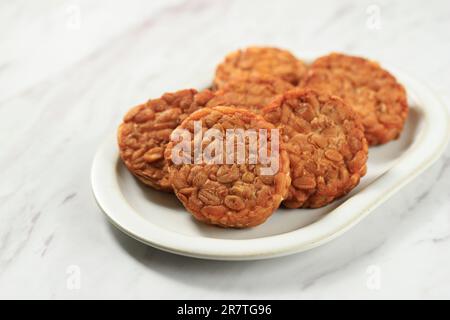 Tempeh rond ou Tempe Goreng. Tempe est un aliment indonésien traditionnel à base de soja fermenté. Banque D'Images