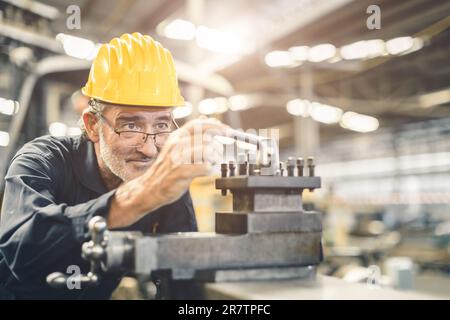 Ingénieur ouvrier senior travaillant avec une grande compétence et précision dans l'usine d'acier métallique de machine à tourner CNC. une fraiseuse saine pour les personnes âgées Banque D'Images