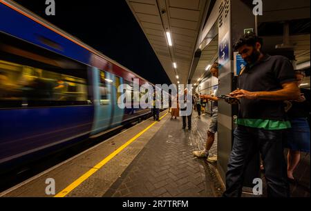 Londres, Royaume-Uni : les passagers attendent tard dans la nuit sur une plate-forme à la gare de London Bridge pendant le départ du train. Banque D'Images