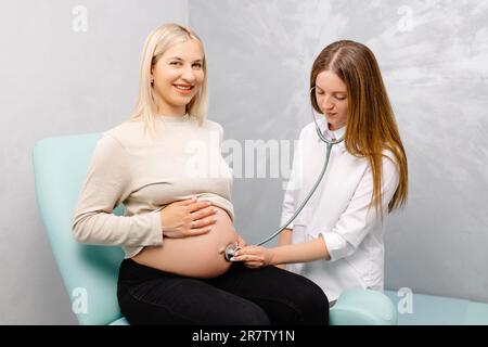 Femme médecin utilisant le stéthoscope examinant la femme enceinte en clinique. Examen médical femme enceinte. Banque D'Images