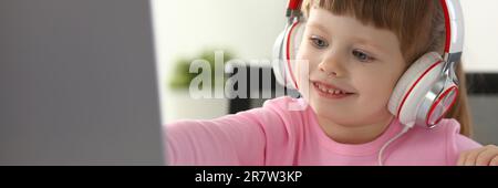 Portrait d'une petite fille dans un casque avec ordinateur portable. Regarder des dessins animés et des enfants concept d'apprentissage à distance Banque D'Images