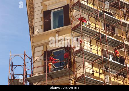 Hommes de travail sur les échafaudages pour la façade d'entretien de l'immeuble d'appartements dans le centre-ville Rome, Italie - avril 22 2023 Banque D'Images